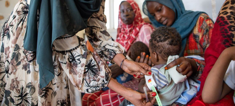 Медик осматривает ребенка на предмет признаков недоедания в Хартуме, Судан.