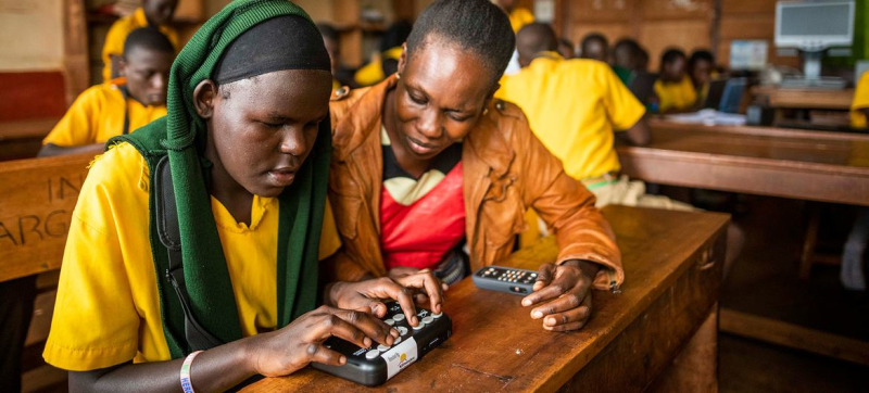 Студентка из Уганды с нарушением зрения использует устройство для записи и чтения шрифта Брайля.