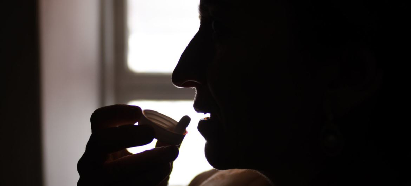 Женщина, живущая с ВИЧ, принимает антиретровирусные препараты у себя дома в Таджикистане.